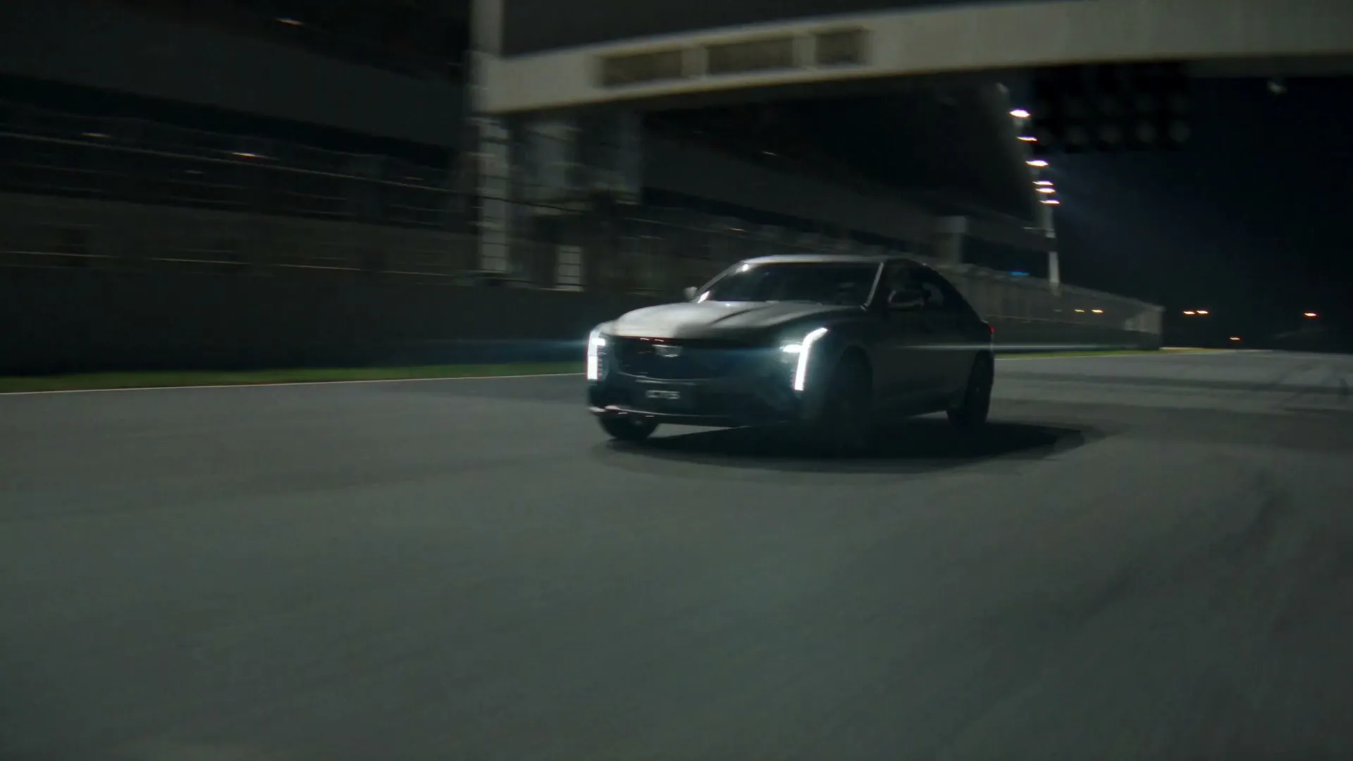 A Cadillac CT5 on a circuit at dusk, headlights on
