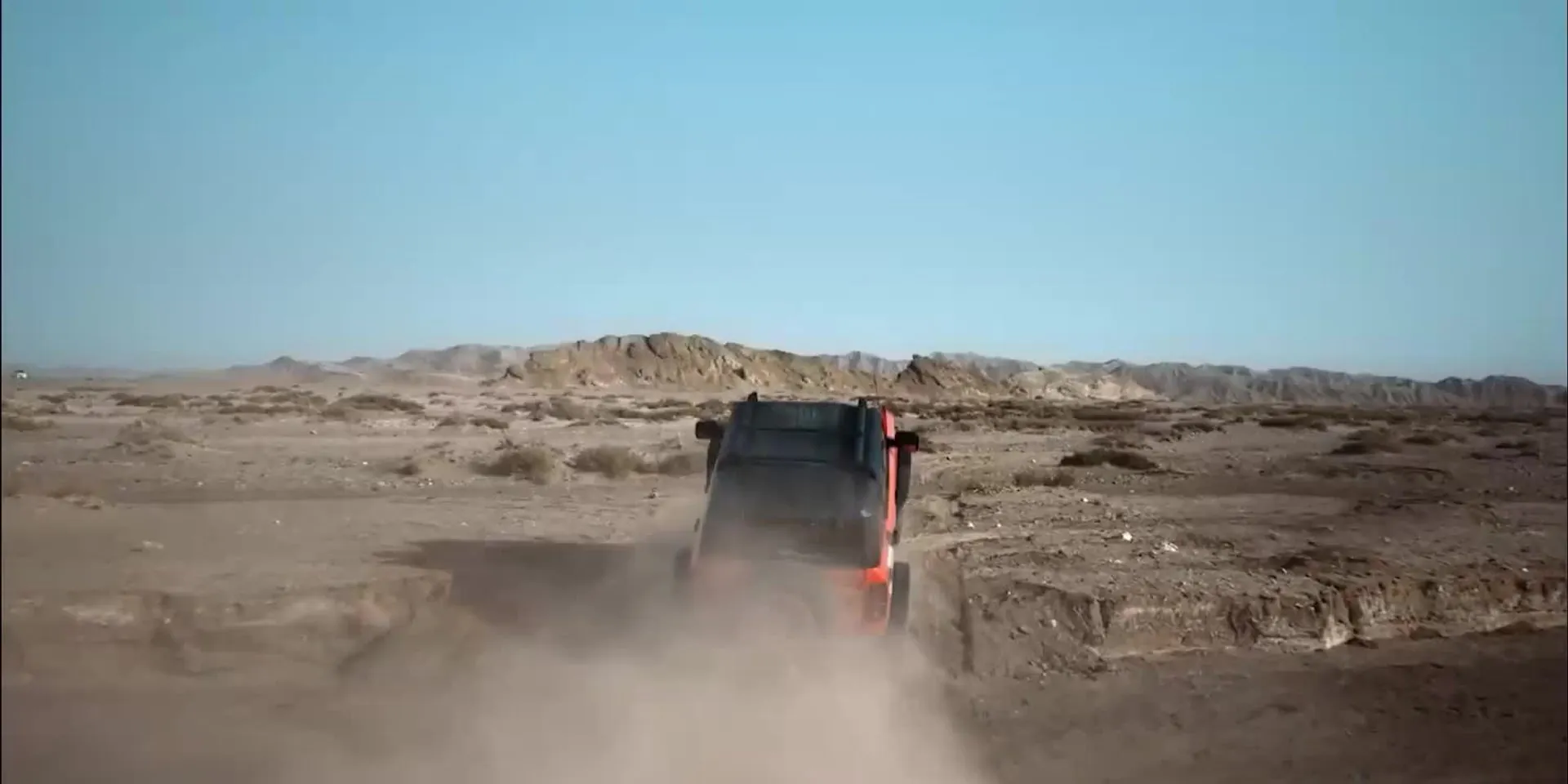 A Bronco driving away through a dust cloud